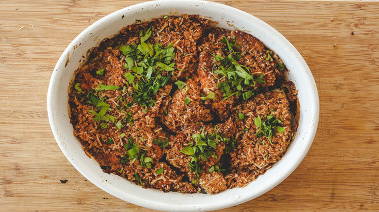 Oval baking dish with breadcrumb-topped baked zucchini.