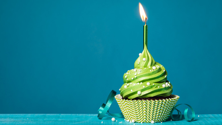 Cupcake with lit candle and green icing