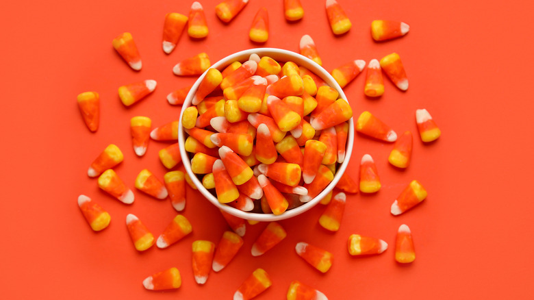 Bowl of candy corn on orange background