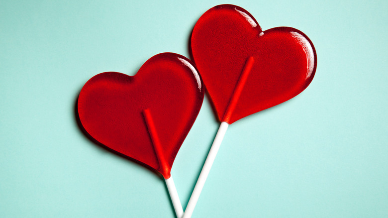 Two heart shaped lollipops on green background