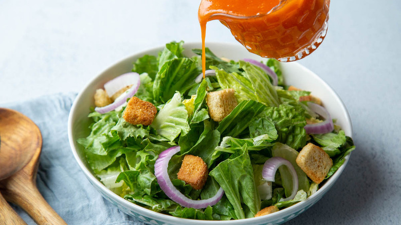 pouring French dressing on salad