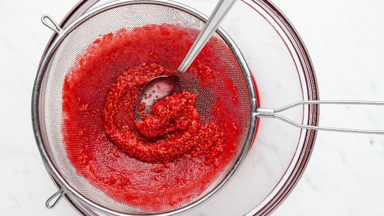 strained raspberry sauce in sieve