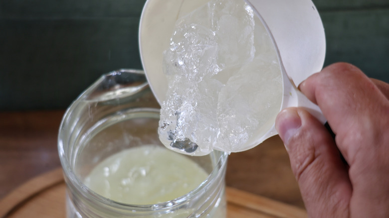 pouring scoop of ice into glass pitcher of champagne margarita