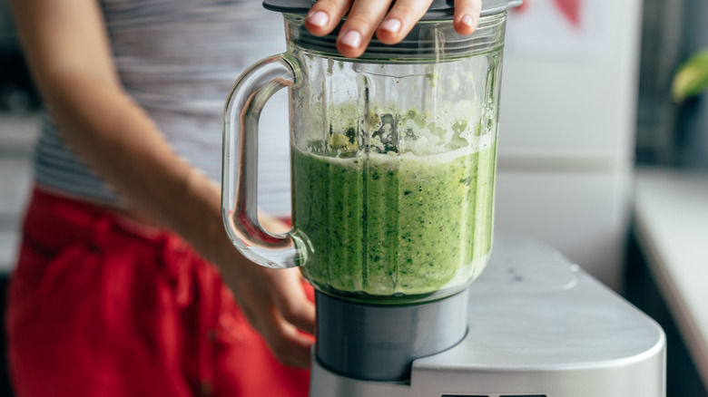 a woman blending green juice