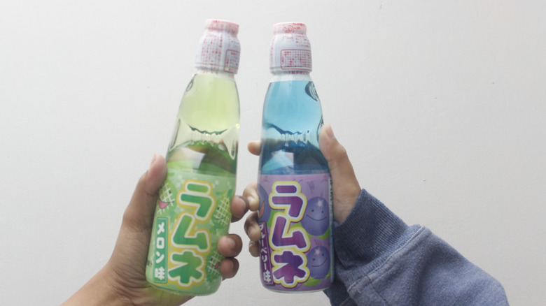 hands holding ramune japanese soda bottles