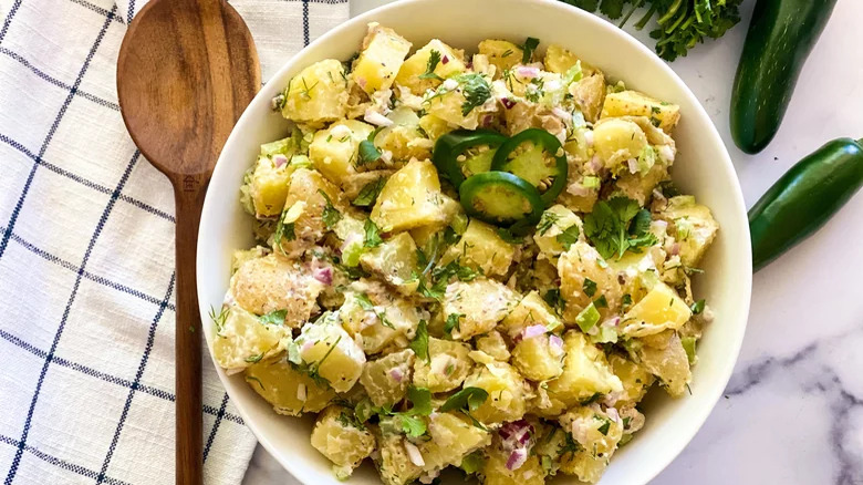 bowl of potato salad with jalapeños and wooden spoon