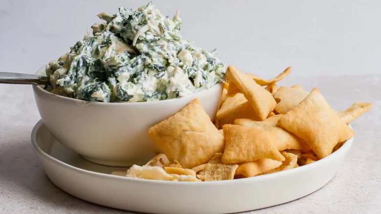 bowl of cold spinach artichoke dip with pita chips 