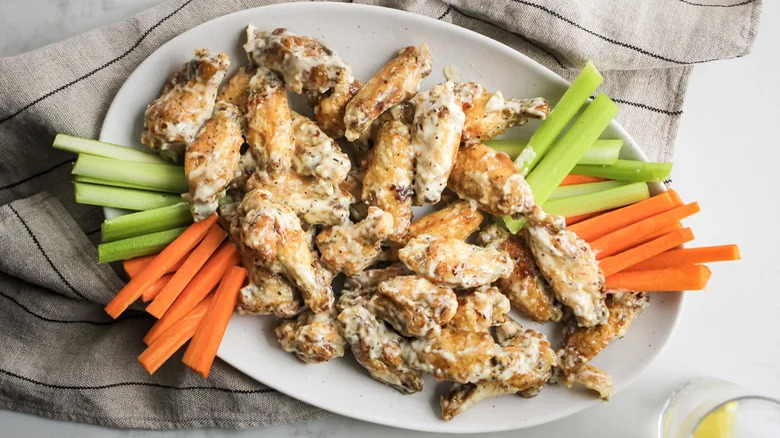 plate of Copycat Buffalo Wild Wings Parmesan Garlic Wings with celery and carrot sticks