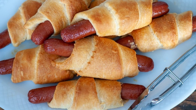 close up of pigs in a blanket with tongs