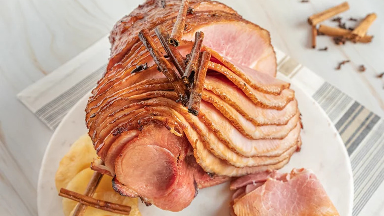 Spiral-sliced ham with pineapple slices and cinnamon sticks.