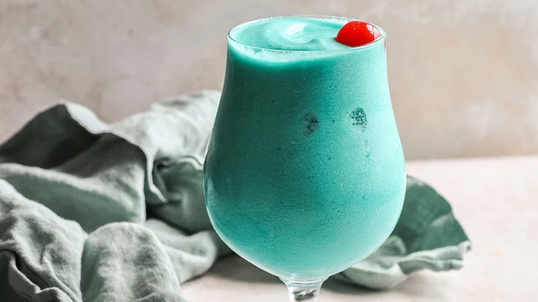 Cocktail glass with frozen blue cocktail and red cherry.