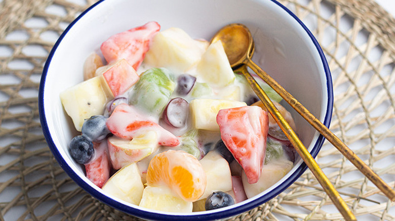 White bowl of fruit salad in a creamy sauce.