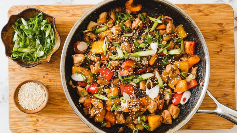 Skillet with mixture of chicken, pineapple, scallions, and peppers.