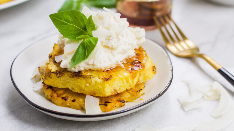 Grilled pineapple slices topped with whipped cream.