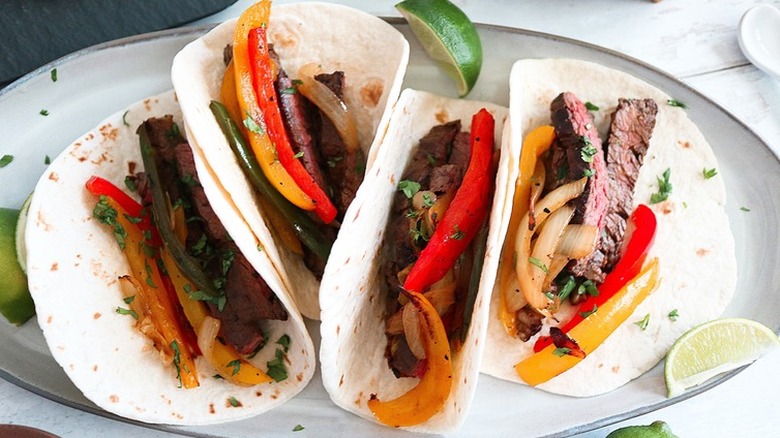 Soft tortillas with sliced peppers, strips of steak, and cilantro.