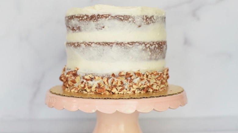 Slice of fruit-filled layer cake and white frosting on plate.