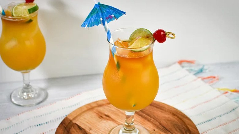 Orange-colored tropical drinks in glasses with paper umbrellas.