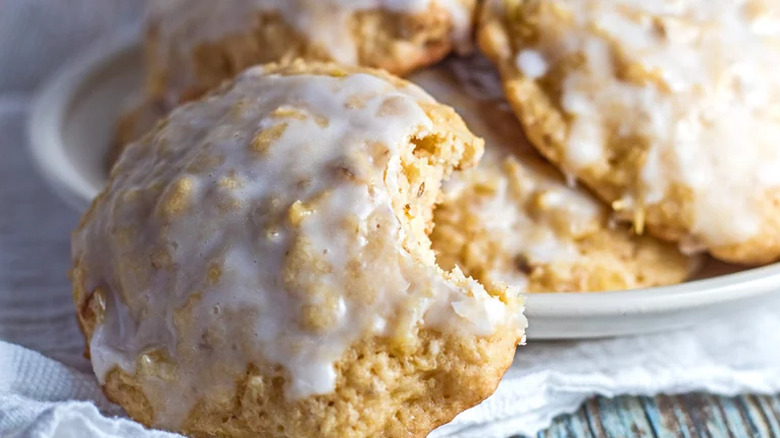 Light-colored iced round cookies with a bite out of one.