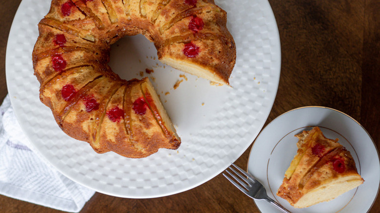 Cherry-topped Bundt cake with slice cut out. 