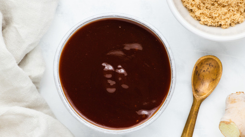 Small dish of dark dipping sauce with wooden spoon.