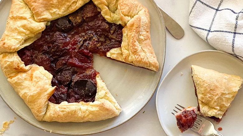 Puff pastry rustic pie with plum filling and slice out. 