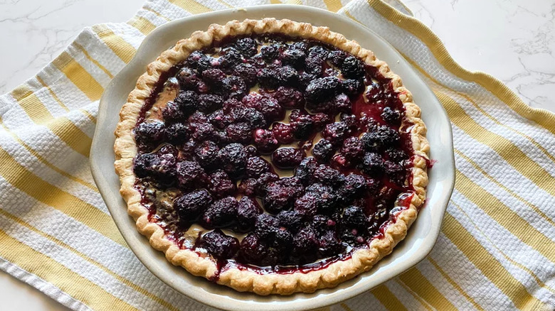 Round baked pie with filling of whole blackberries. 