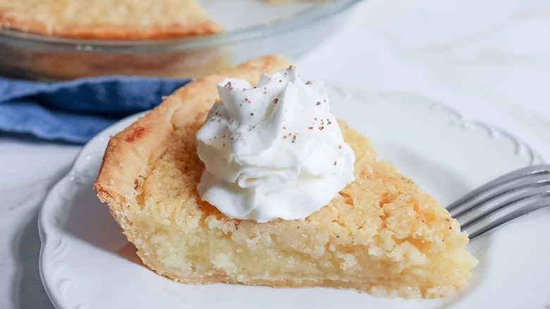 Slice of buttermilk pie with whipped cream.