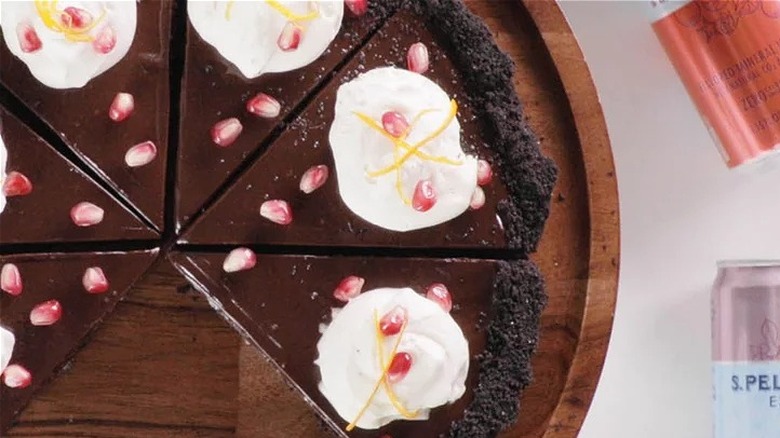 Sliced chocolate tart with pomegranate seeds and cream. 