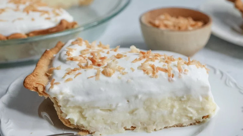 Slice of coconut cream pie with toasted coconut on top.