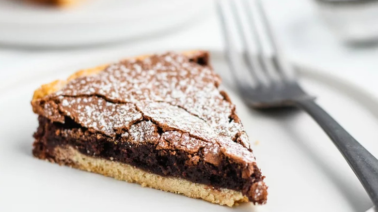 Slice of fudge pie with cookie bottom and powdered sugar top.