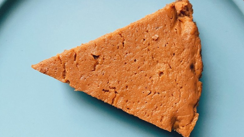 Triangular slice of pumpkin pie on a blue plate.