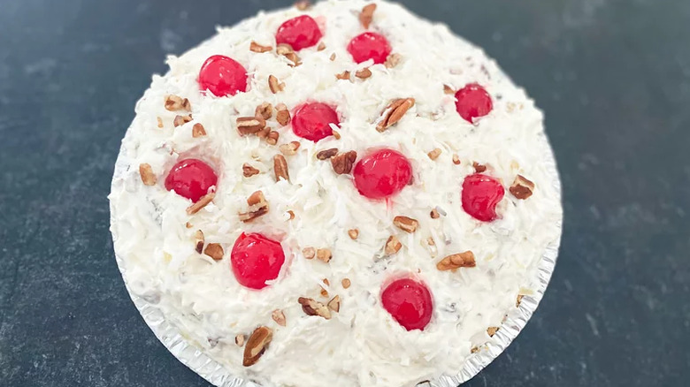 Cream-topped pie with coconut, pecans, and maraschino cherries.