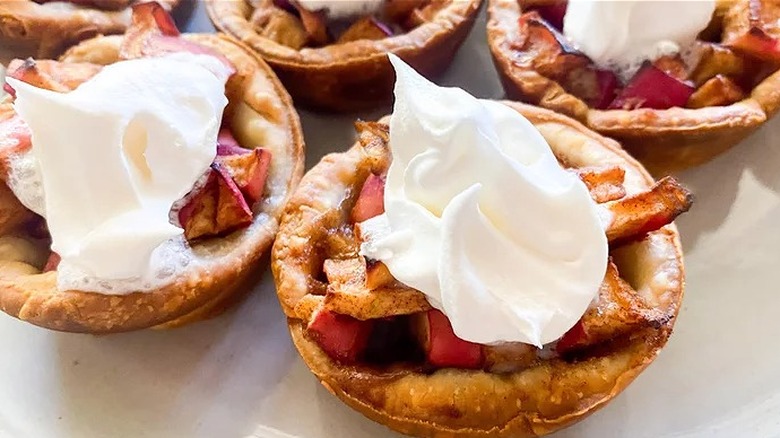 Miniature pies with diced apples and whipped cream.