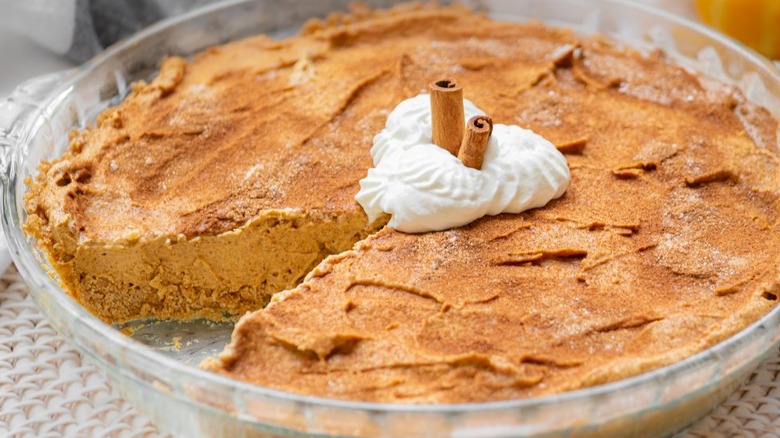 Pumpkin cheesecake pie in pie plate with slice out. 