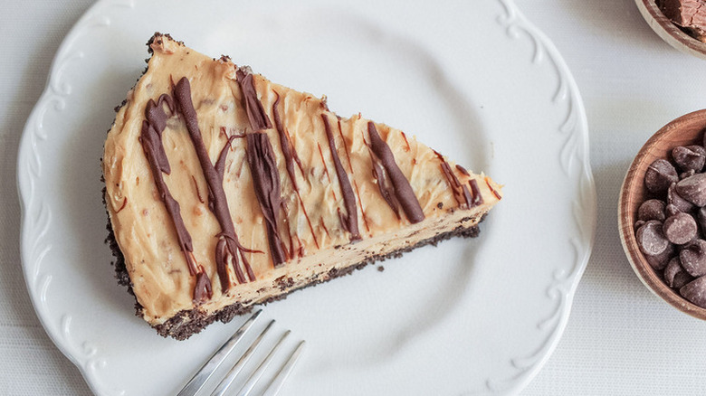 Slice of peanut butter pie with chocolate crust and topping.