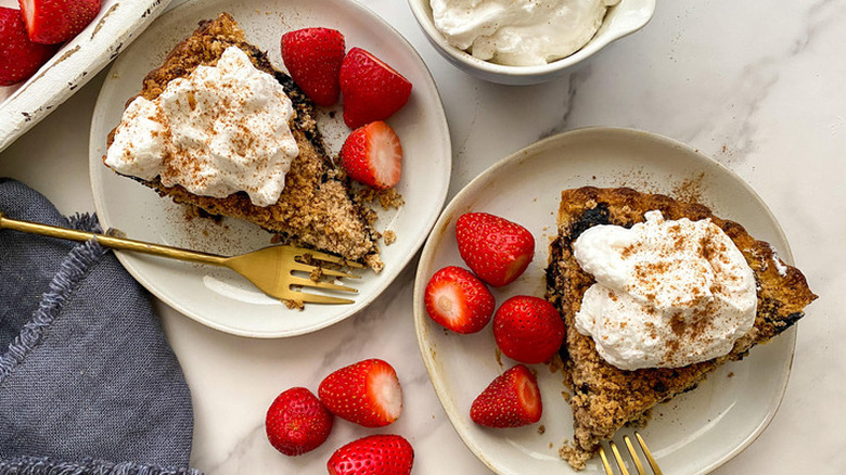 Two slices of crumb-topped molasses pie with cream and berries.