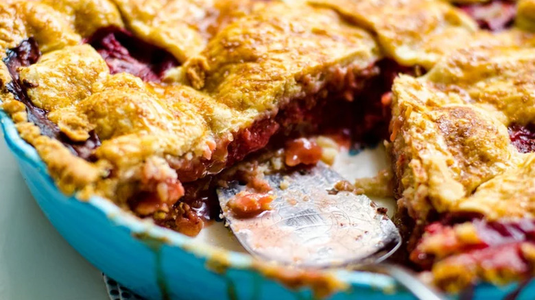 Strawberry pie in blue dish with slice cut out. 