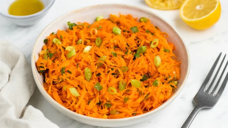 Bowl of shredded carrot salad on white tablecloth