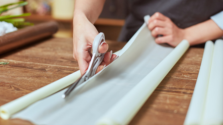 Woman's hands cutting white paper with scissors