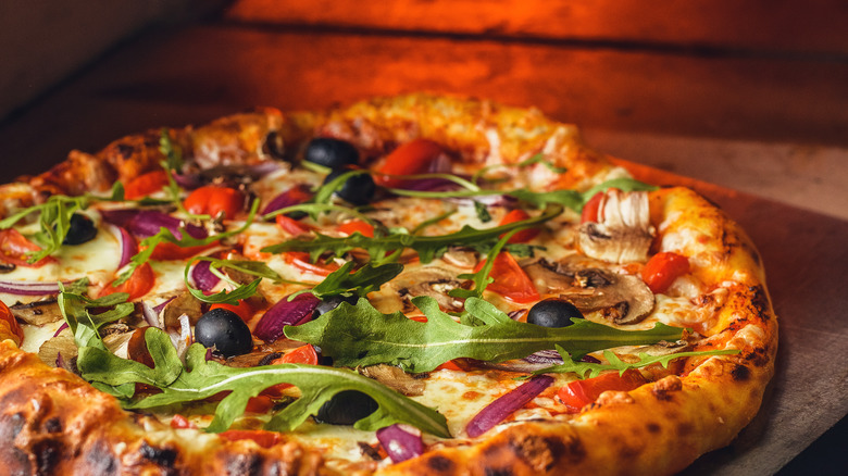 Vegetable pizza with oven in background