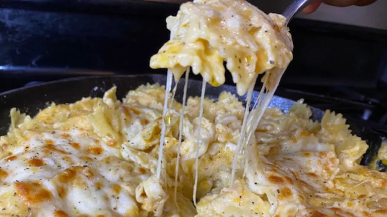 Forkful of creamy mac and cheese from skillet.