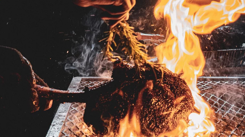 Tomahawk steak over a flaming grill.