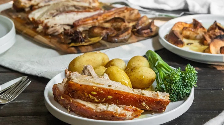 Pork belly on plate with potatoes and broccoli. 