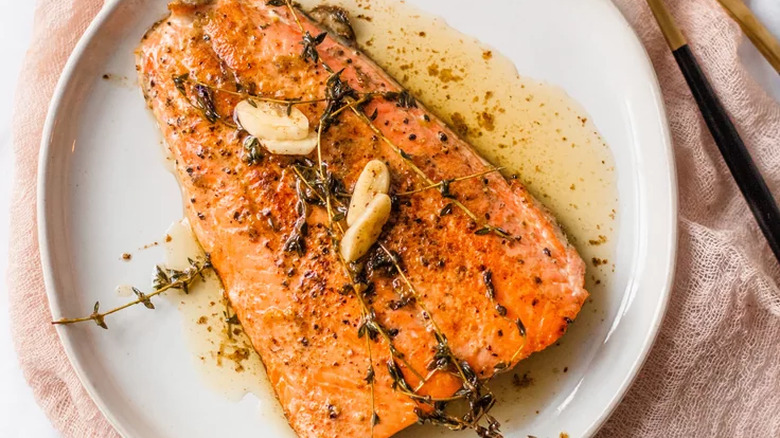 Salmon filet on plate with thyme and garlic. 