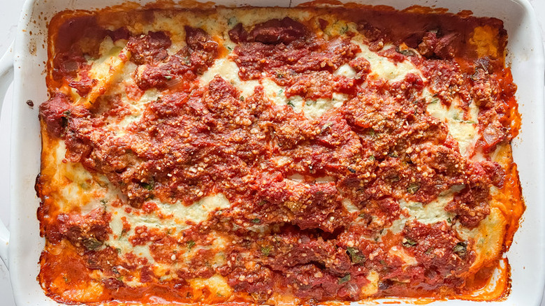 Rectangular pan of baked lasagna with red sauce.