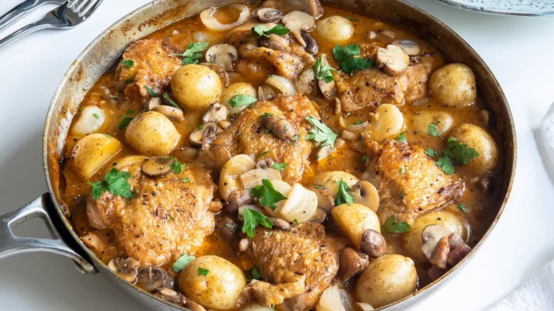 Large skillet with chicken, mushrooms and potatoes in sauce.