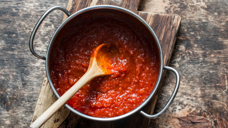 Homemade tomato sauce in pot with wooden spoon.