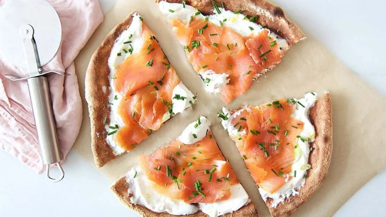 Quartered pizza with salmon and creamy topping.