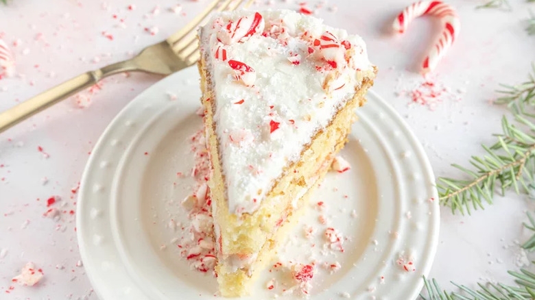 Slice of white frosted cake with candy cane bits
