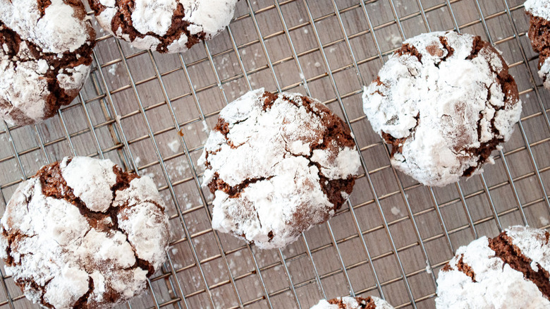 Several sugar-coated chocolate crinkle cookies on rack